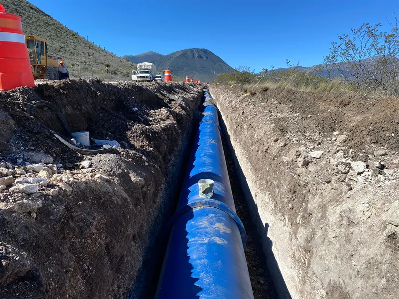 Tubería de hierro dúctil instalada en zanja con montañas al fondo