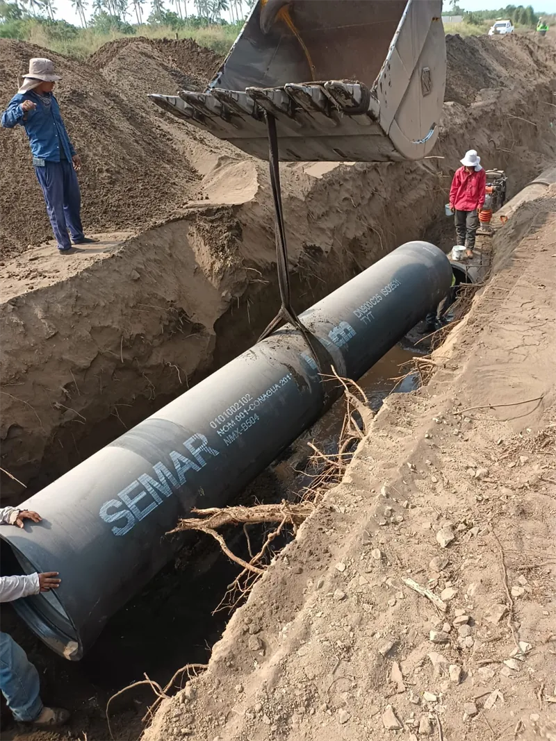 Excavadora colocando tubería de hierro dúctil de 36″