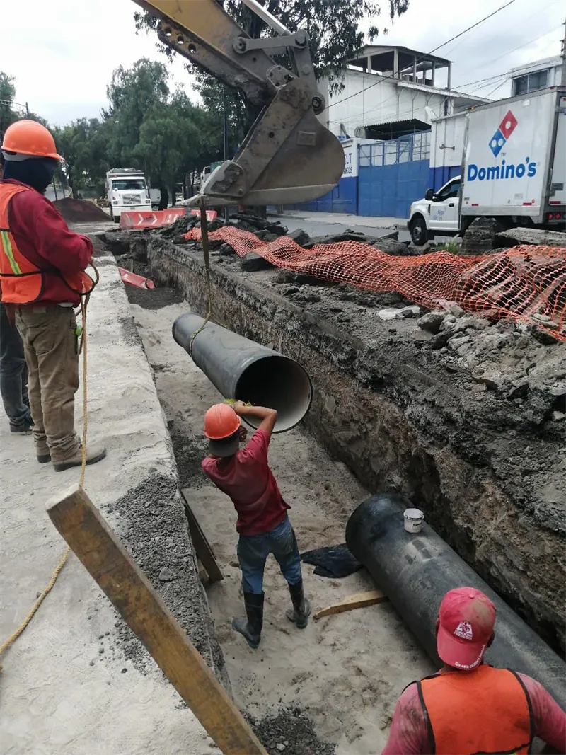 Cuadrilla bajando tubería de hierro dúctil a la zanja