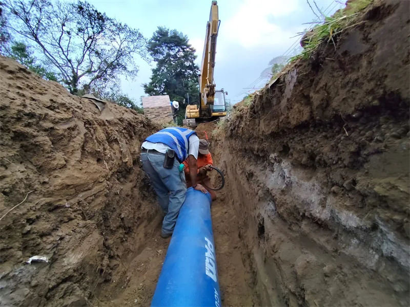 Trabajador instalando tubería de hierro dúctil dentro de la zanja