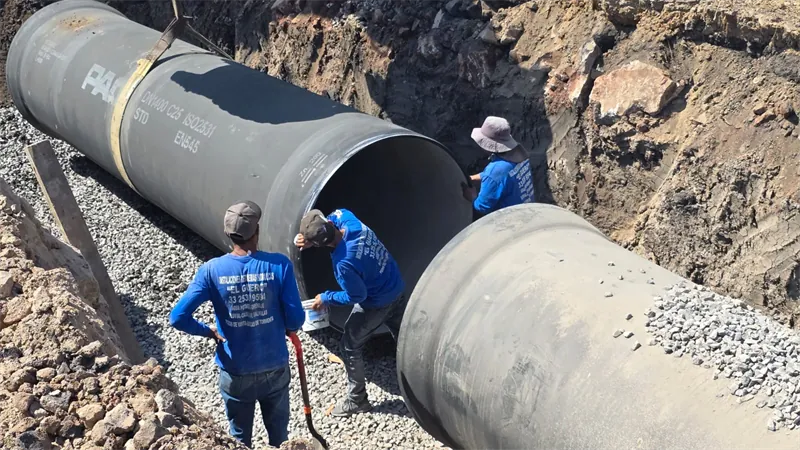 Cuadrilla junto a tubería de hierro dúctil de 56″ en la zanja