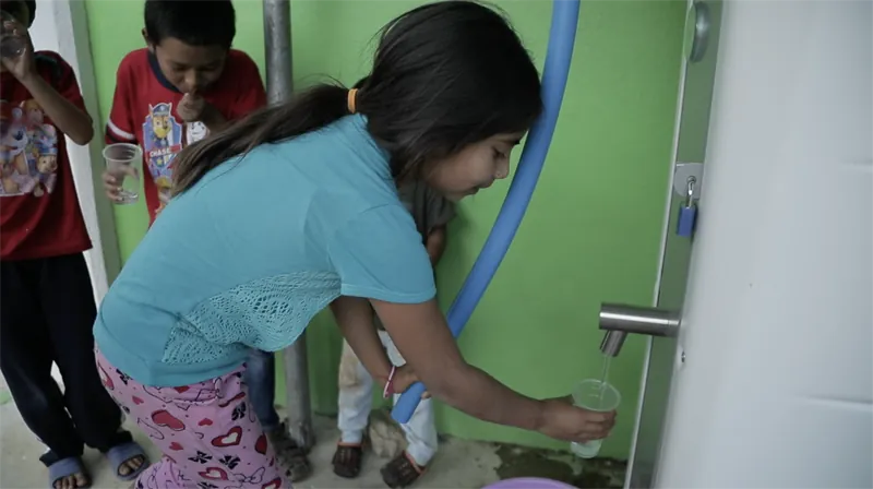 Niña tomando agua potable de la planta Villagepump